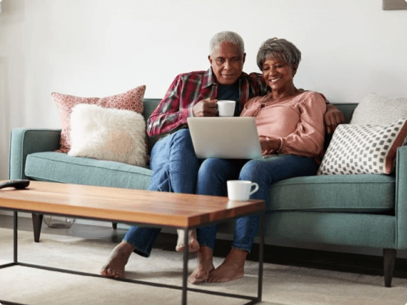 Una pareja de ancianos sonriendo y abrazándose en su cocina.
