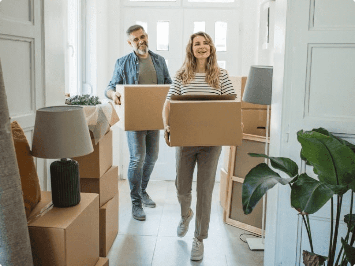 Pareja cargando cajas hacia una casa